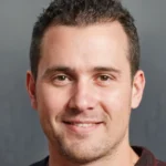 Smiling man with short dark hair and light stubble